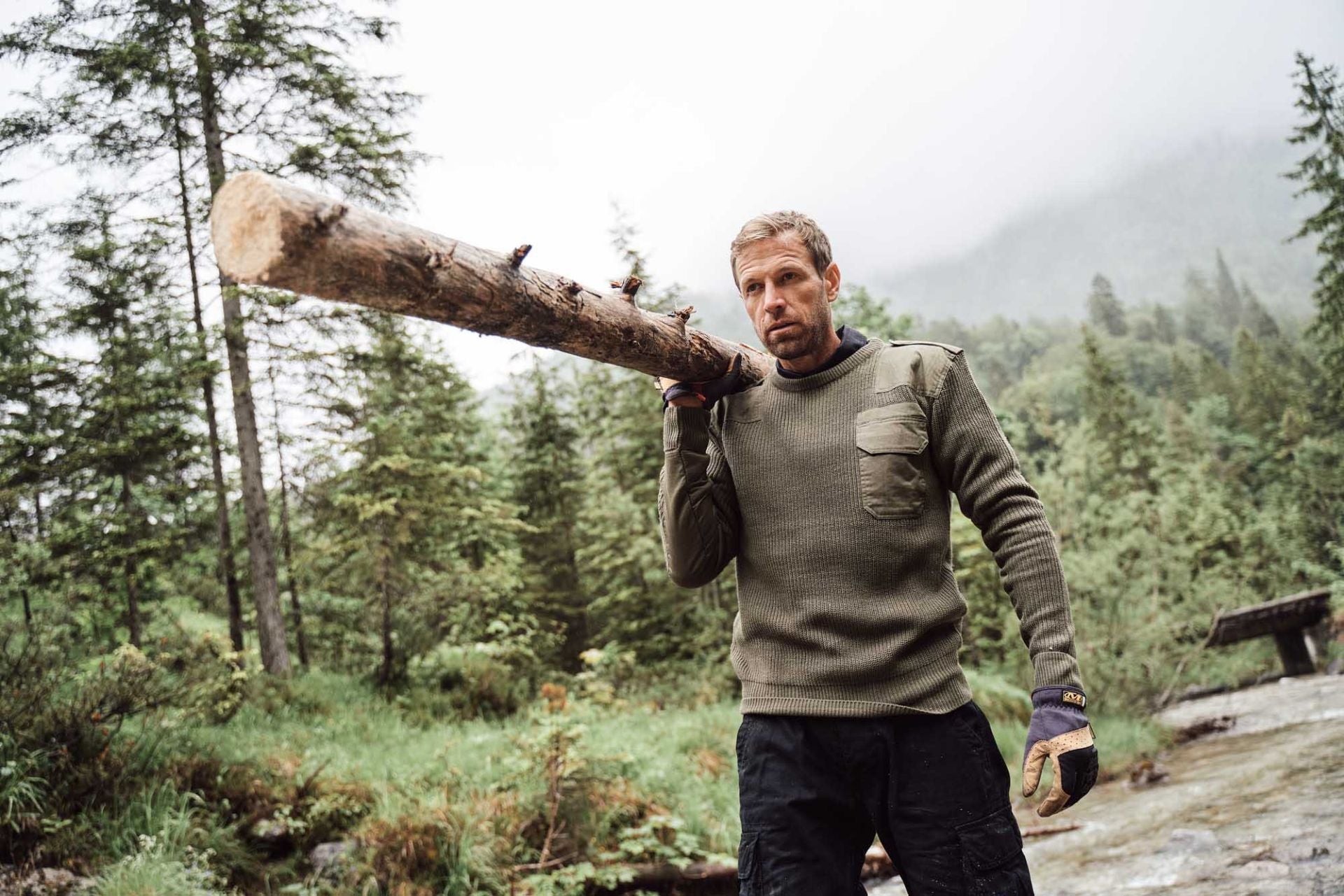 `Model trägt BW Strickpullover in Oliv beim Outdoor-Einsatz im Wald`
