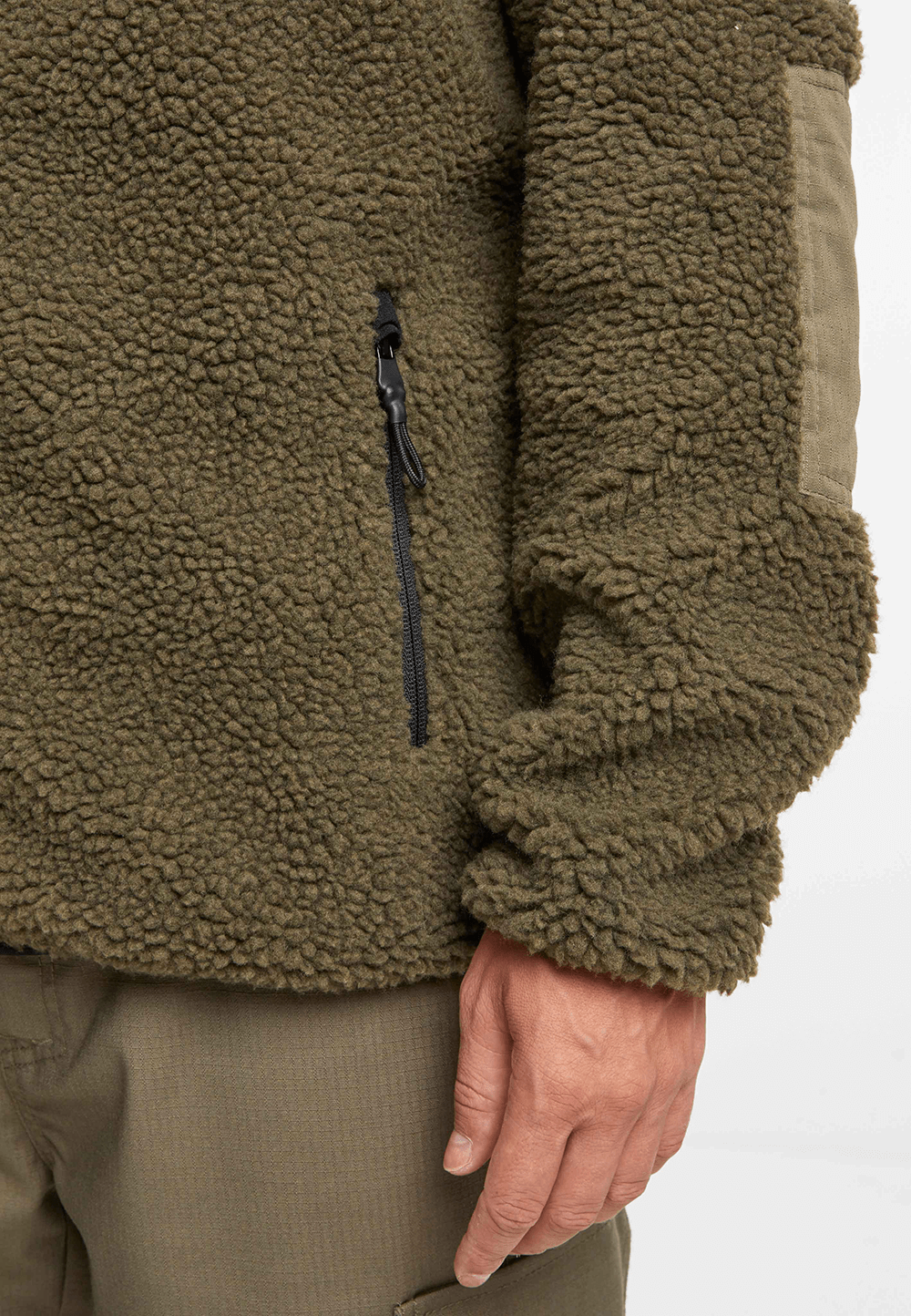 `Detailaufnahme einer taktischen Teddyfleece Jacke in Oliv mit Reißverschlusstasche`
