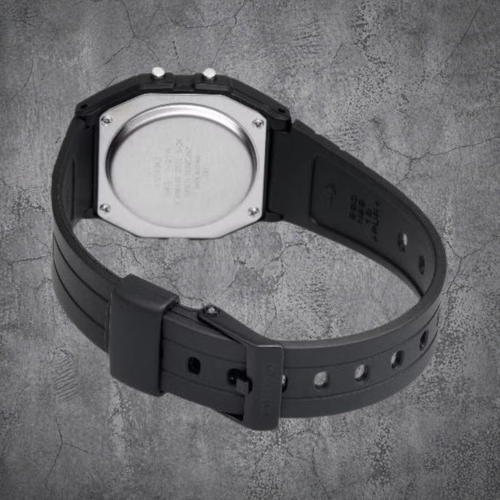 `Rückansicht der schwarzen CASIO F-91W-1YEG Armbanduhr mit Resin-Armband auf grauem Betonhintergrund`
