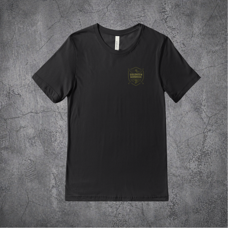`Schwarzes SoldatenSchmiede Tactical-Shirt mit dezentem Frontlogo auf grauem Betonhintergrund`
