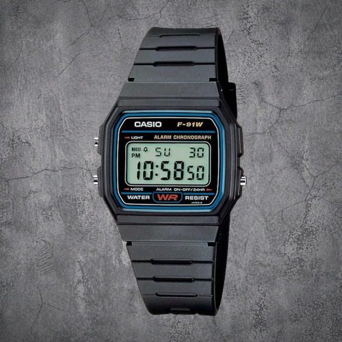 Schwarze CASIO F-91W-1YEG Digitaluhr mit Resin-Armband in Frontansicht auf grauem Betonhintergrund