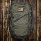 `Olivgrüner Eberlestock Tactical Rucksack mit MOLLE-System und Outdoor-Ausrüstung auf rustikalem Holzuntergrund`
